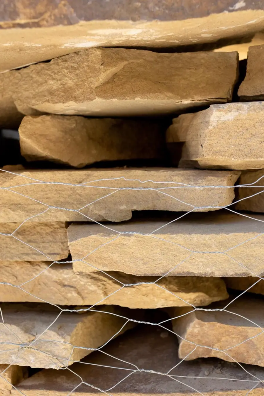 Stacked slabs of tan flagstone bound in wire